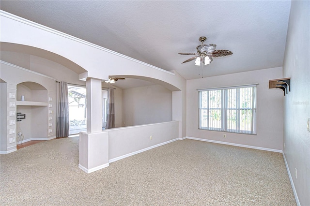 unfurnished room featuring built in shelves, a textured ceiling, light colored carpet, and ceiling fan