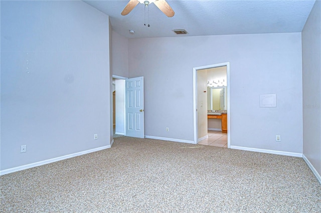 unfurnished bedroom featuring ceiling fan, ensuite bathroom, a textured ceiling, vaulted ceiling, and light colored carpet