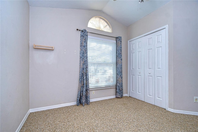 unfurnished bedroom featuring carpet floors, vaulted ceiling, and a closet