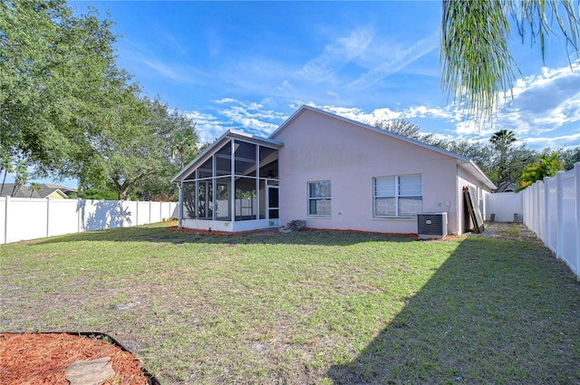 rear view of property with a yard, central AC, and a sunroom