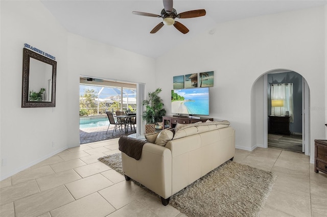 living area featuring high vaulted ceiling, arched walkways, ceiling fan, and light tile patterned floors