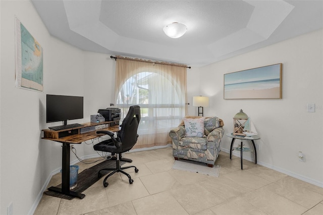 office space featuring a raised ceiling, light tile patterned flooring, and baseboards