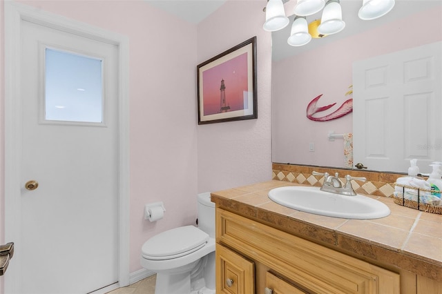 bathroom featuring tasteful backsplash, vanity, toilet, and an inviting chandelier