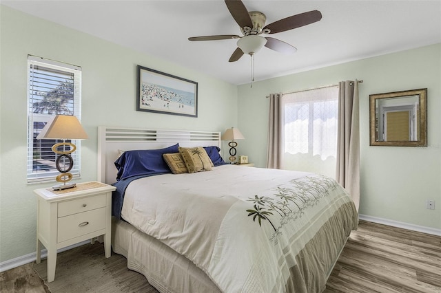 bedroom with ceiling fan, wood finished floors, and baseboards