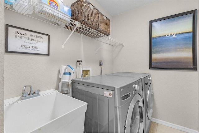 laundry room with laundry area, light tile patterned floors, baseboards, washer and clothes dryer, and a sink