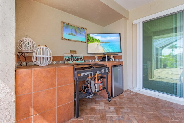 bar featuring freestanding refrigerator and a textured wall