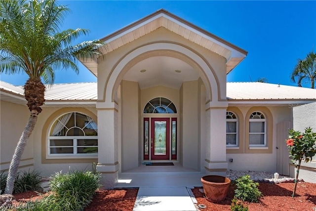 doorway to property featuring metal roof and stucco siding