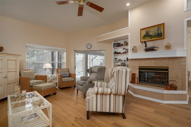 living room with ceiling fan, a fireplace, and light wood-type flooring