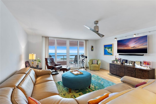 living room featuring ceiling fan, floor to ceiling windows, and light hardwood / wood-style floors