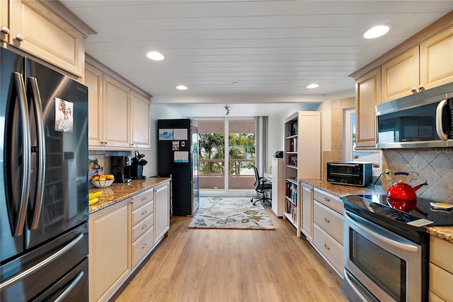 kitchen with light wood-type flooring, appliances with stainless steel finishes, backsplash, and light stone counters