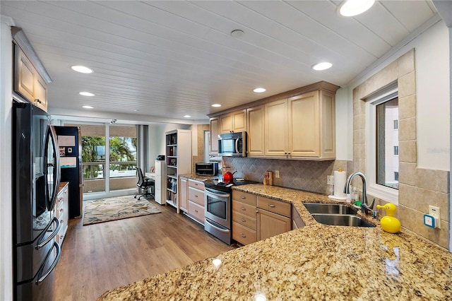 kitchen featuring stainless steel appliances, light brown cabinetry, sink, backsplash, and light hardwood / wood-style flooring