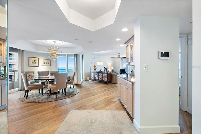 dining space with ceiling fan, light hardwood / wood-style flooring, and a tray ceiling