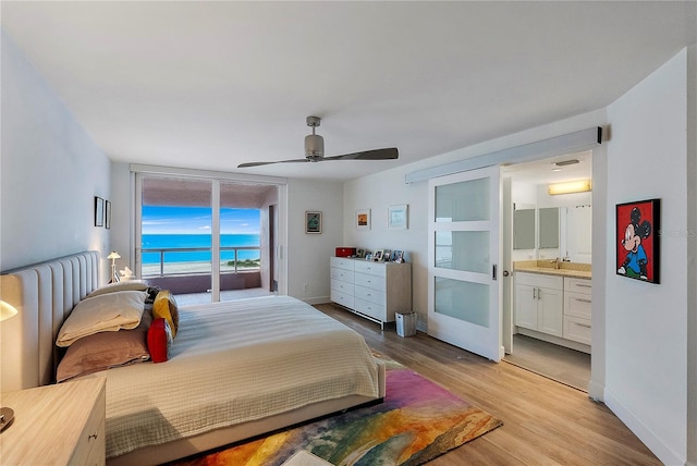 bedroom with connected bathroom, sink, access to outside, light wood-type flooring, and ceiling fan