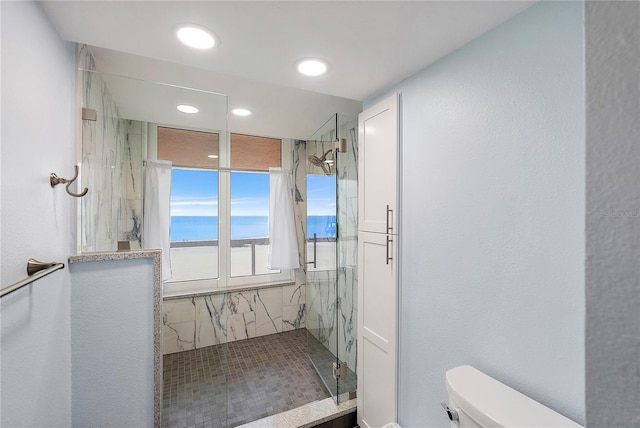 bathroom with toilet, tiled shower, and a water view