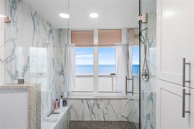 bathroom featuring a view of the beach, a water view, and an enclosed shower