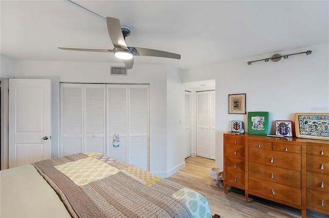 bedroom featuring ceiling fan, two closets, and light hardwood / wood-style flooring