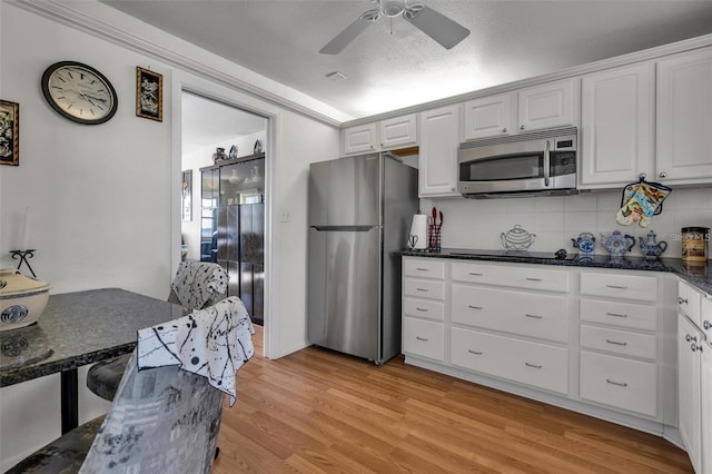 kitchen with white cabinetry, stainless steel appliances, backsplash, a textured ceiling, and light hardwood / wood-style flooring