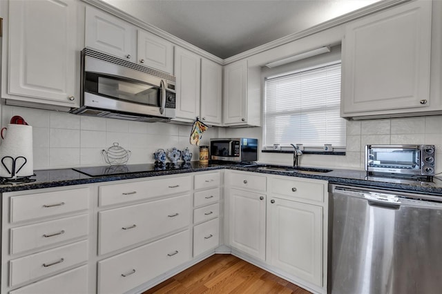 kitchen with white cabinetry, stainless steel appliances, light hardwood / wood-style floors, sink, and decorative backsplash