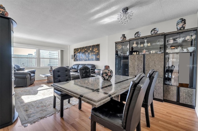 dining room with hardwood / wood-style flooring, a textured ceiling, and a notable chandelier