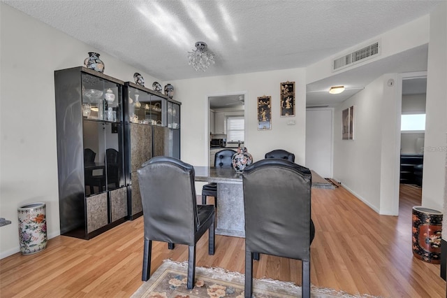 dining space featuring a textured ceiling and light hardwood / wood-style flooring