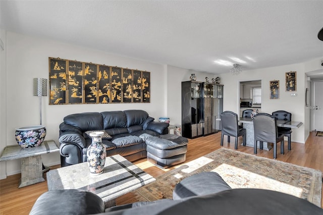 living room featuring light wood-type flooring and a textured ceiling