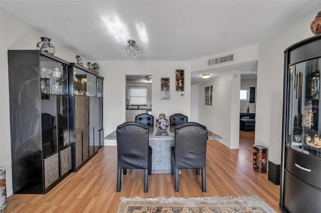 dining area featuring ceiling fan, a textured ceiling, and light wood-type flooring