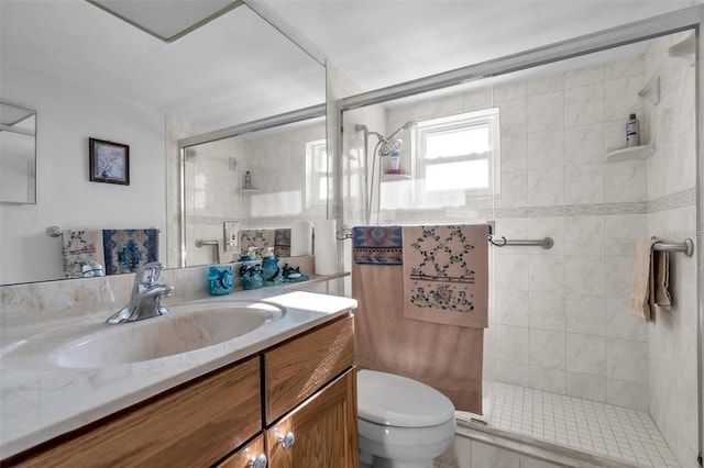 bathroom featuring a shower with door, toilet, and vanity