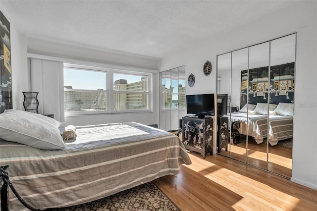 bedroom with hardwood / wood-style flooring, multiple windows, and a textured ceiling