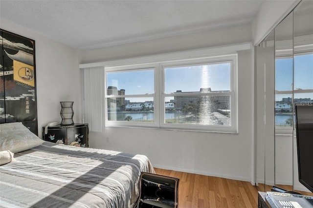 bedroom featuring a textured ceiling, multiple windows, and hardwood / wood-style floors