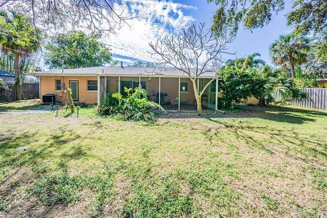 rear view of house with central AC unit and a lawn