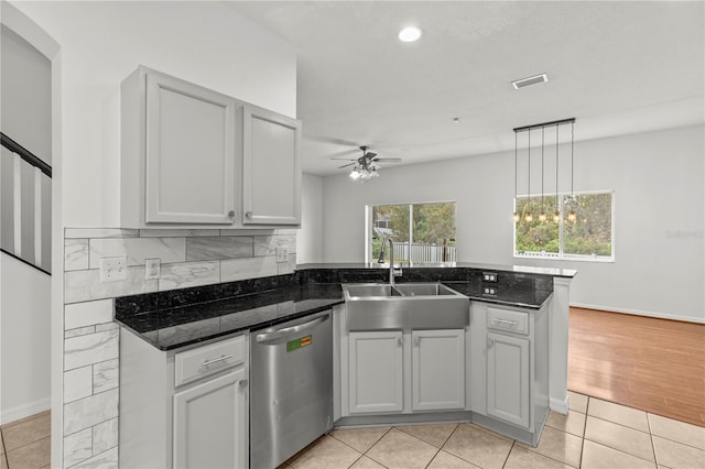 kitchen with dishwasher, kitchen peninsula, sink, light tile patterned floors, and ceiling fan with notable chandelier