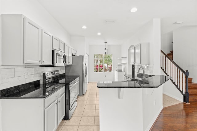 kitchen featuring light tile patterned floors, stainless steel appliances, decorative backsplash, and kitchen peninsula