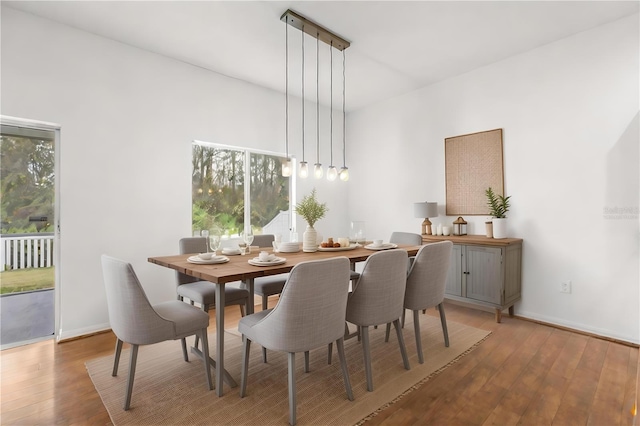 dining space featuring hardwood / wood-style flooring, a towering ceiling, and plenty of natural light