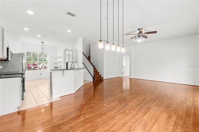 unfurnished living room featuring ceiling fan, light hardwood / wood-style floors, and sink