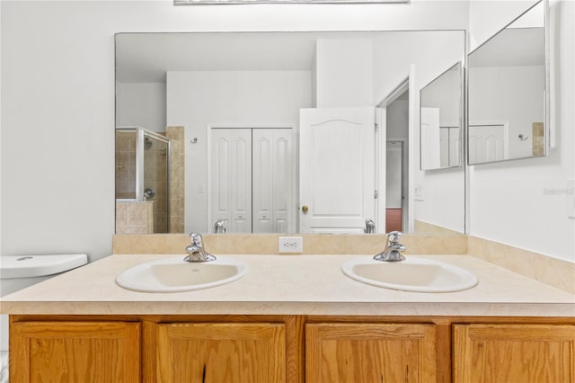 bathroom featuring a shower with shower door, vanity, and toilet