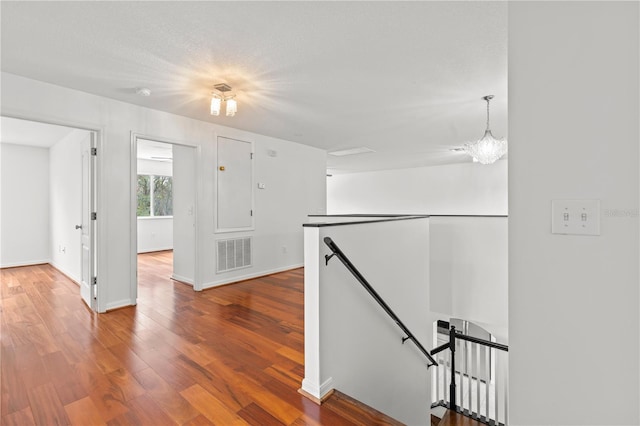 hallway with hardwood / wood-style flooring and a notable chandelier