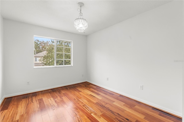 spare room with light hardwood / wood-style flooring and a notable chandelier