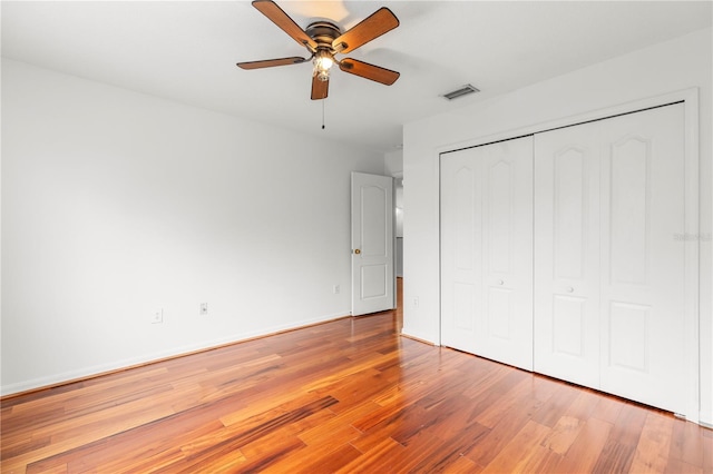 unfurnished bedroom with ceiling fan, wood-type flooring, and a closet