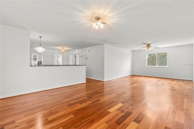 unfurnished living room with light wood-type flooring and a chandelier