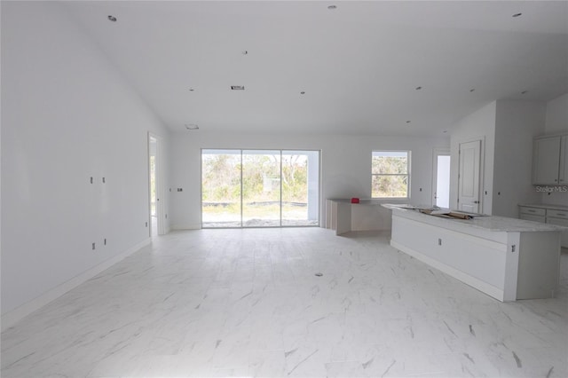 interior space featuring high vaulted ceiling, white cabinetry, and a center island