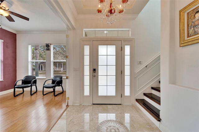 entrance foyer featuring crown molding and ceiling fan with notable chandelier