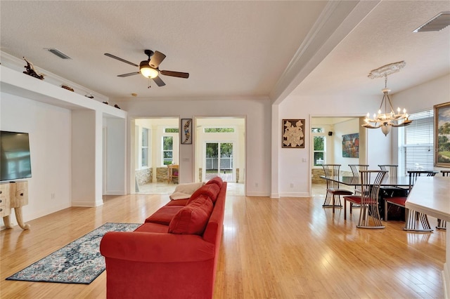 living room with crown molding, ceiling fan with notable chandelier, a textured ceiling, and light hardwood / wood-style flooring