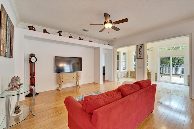 living room with a textured ceiling, ornamental molding, light hardwood / wood-style floors, and ceiling fan