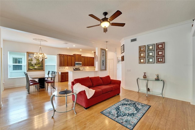 living room with ornamental molding, light hardwood / wood-style floors, and ceiling fan with notable chandelier