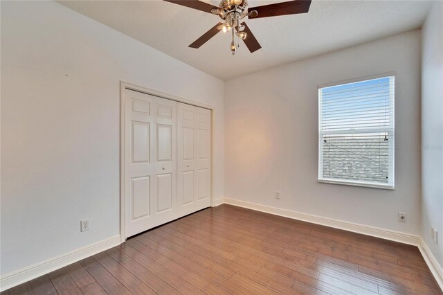 unfurnished bedroom with hardwood / wood-style flooring, ceiling fan, and a closet