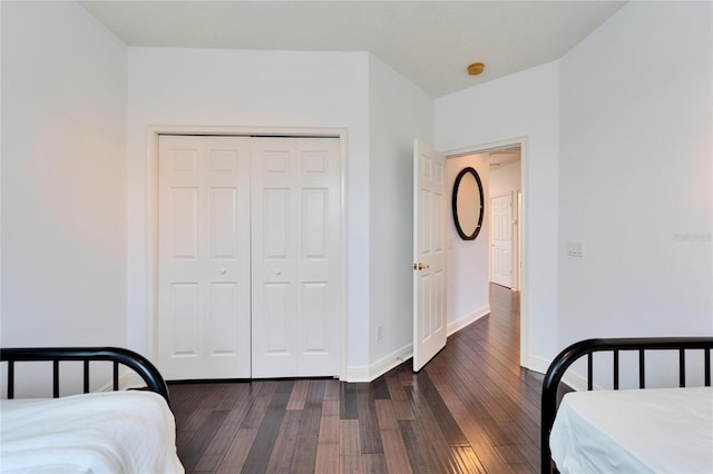 bedroom with dark hardwood / wood-style floors and a closet