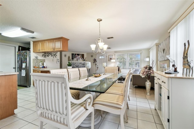 tiled dining room featuring a notable chandelier and a textured ceiling