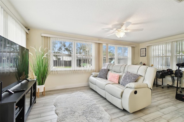 living room with ceiling fan, light hardwood / wood-style floors, and a textured ceiling