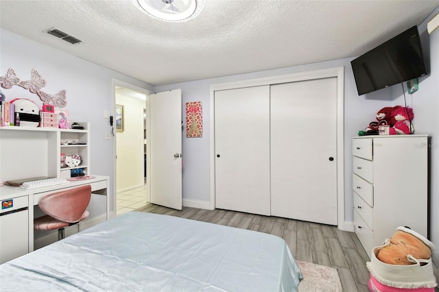 bedroom featuring light hardwood / wood-style floors, a textured ceiling, and a closet