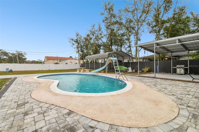 view of pool featuring a grill, a patio area, a carport, and a water slide